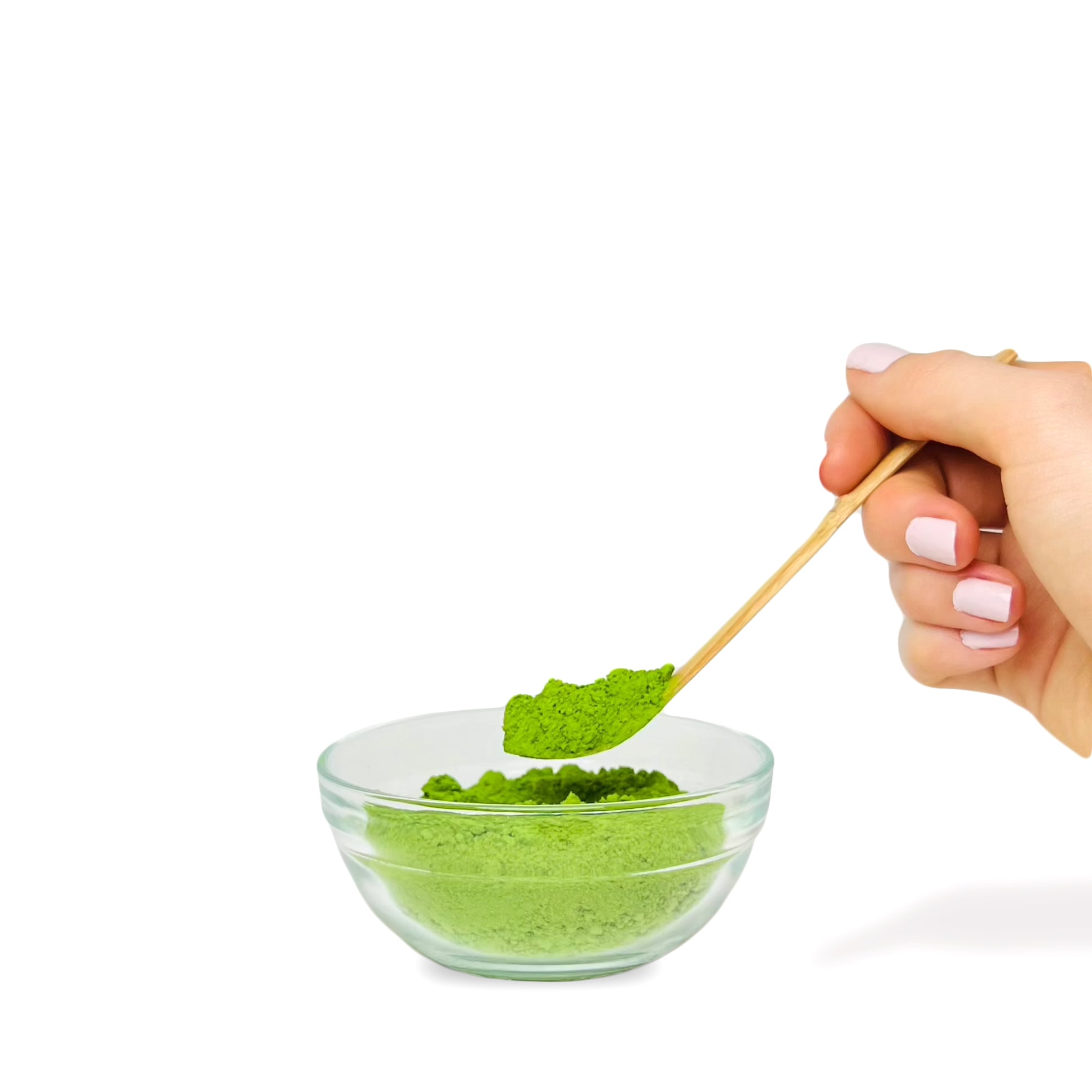 A hand scooping bright green matcha from a bowl with a bamboo chashaku