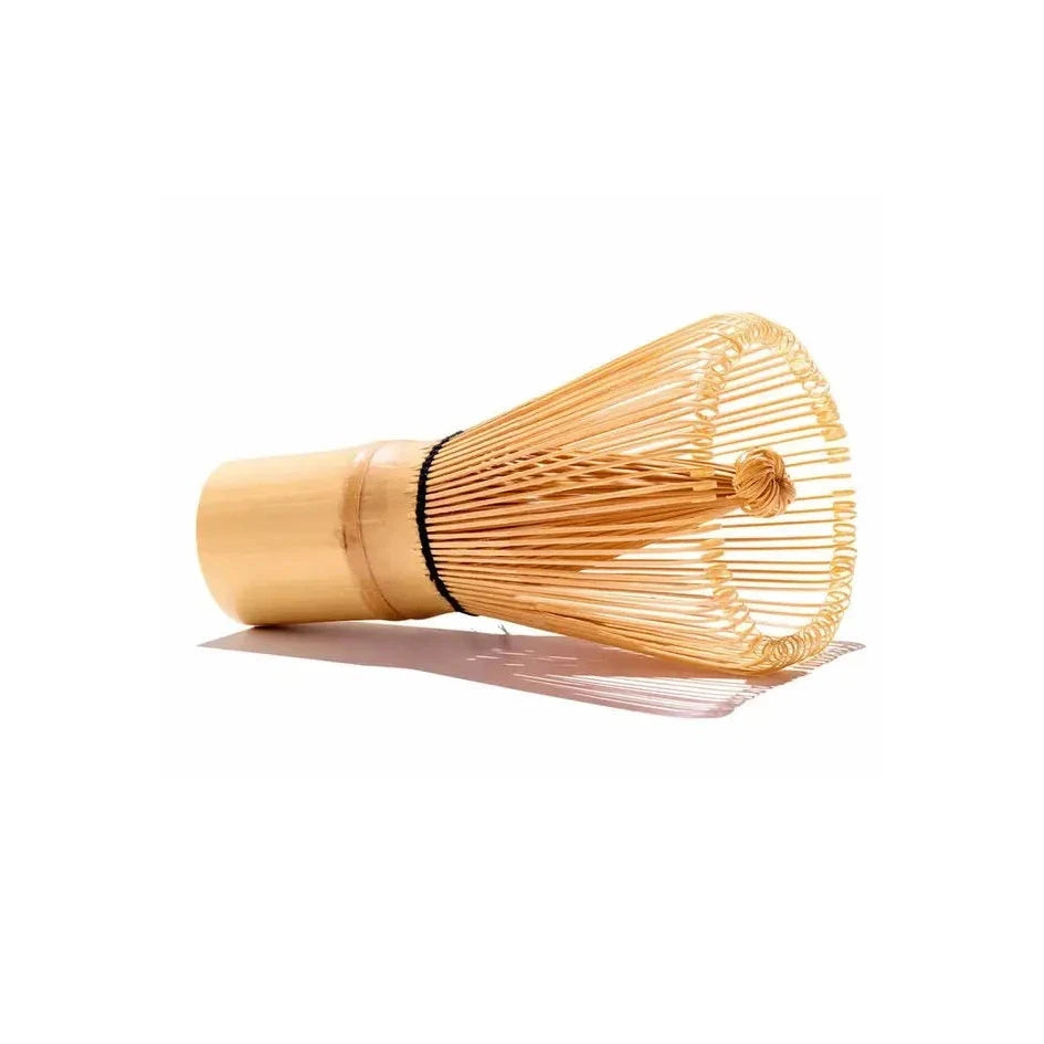 A bamboo whisk laid on its side with a white background